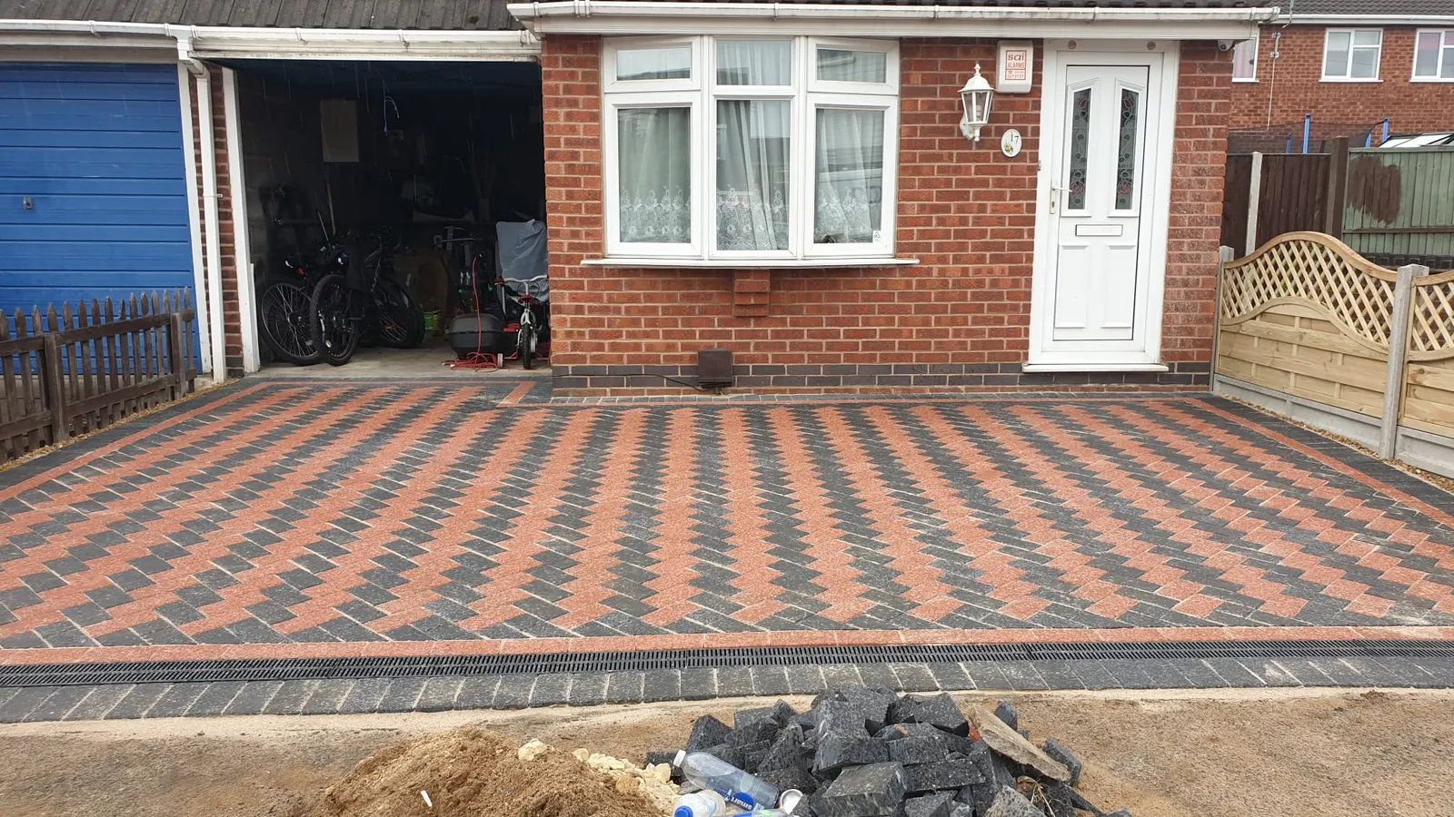 Red and charcoal block paving driveway in front of a bungalow garage
