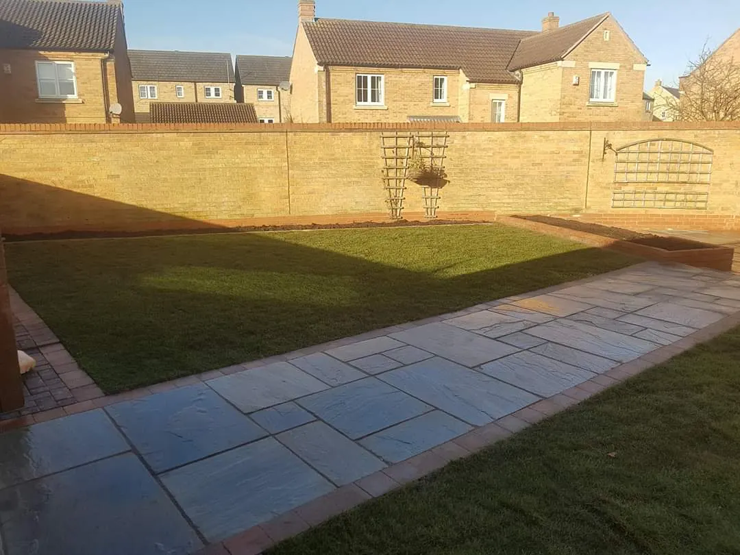 Sandstone path alongside a new lawn in a walled garden