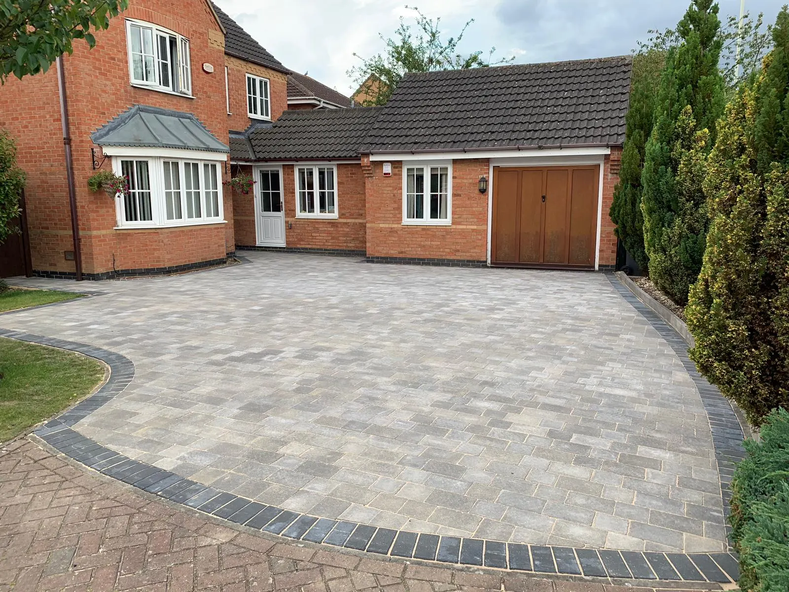 Silver block paving driveway with a curved charcoal border at a detached house