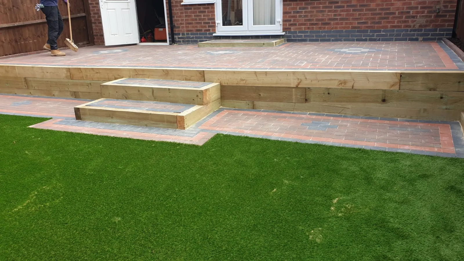 Sleeper steps up to a block paving terrace above artificial grass