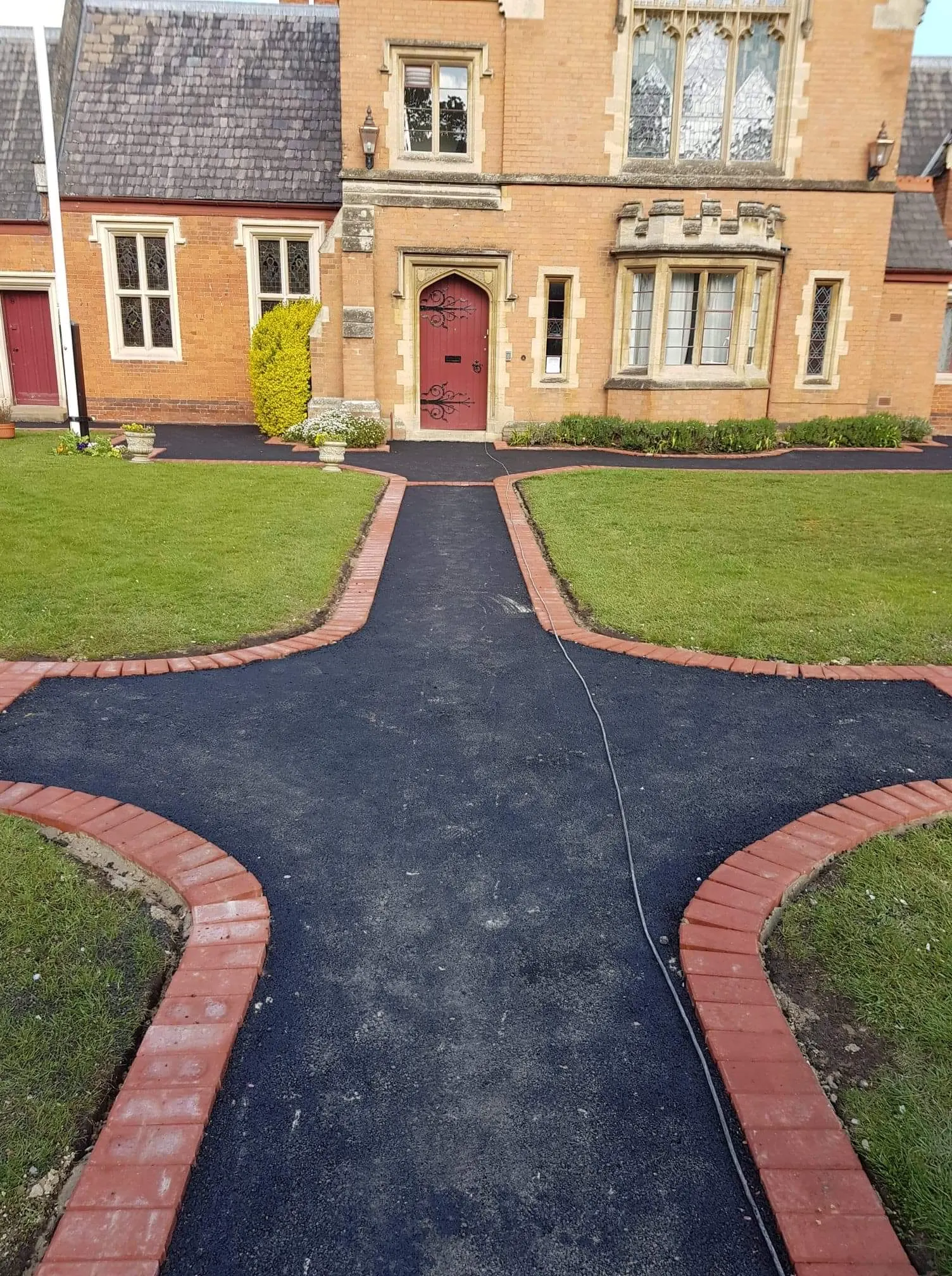 Tarmac paths meeting at a junction, edged in red block paving