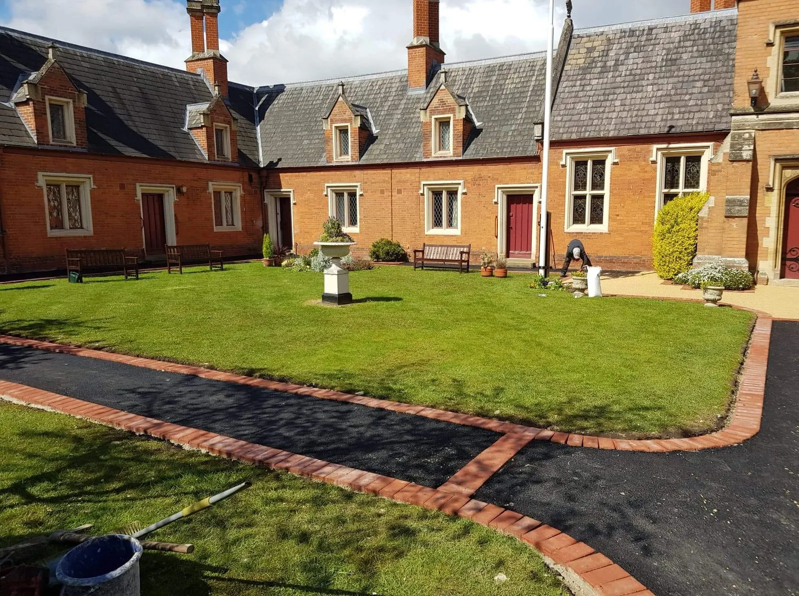New tarmac paths edged in red block paving around a courtyard lawn